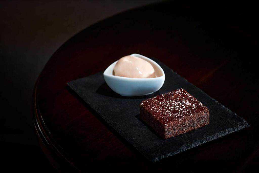 a plate with a bowl of ice cream and a piece of cake at NH Sintra Centro in Sintra