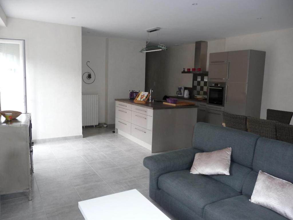 un salon avec un canapé bleu et une cuisine dans l'établissement Maison de ville tout confort, à La Teste-de-Buch