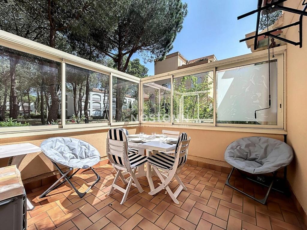 un patio avec une table, des chaises et des fenêtres dans l'établissement 3653-Studio climatisé avec terrasse à 400m de la plage, à Argelès-sur-Mer
