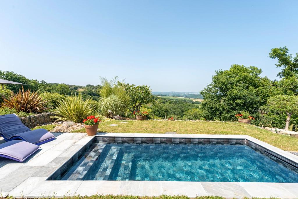 a swimming pool in the yard of a house with two chairs at L'Atelier de Scarlett 