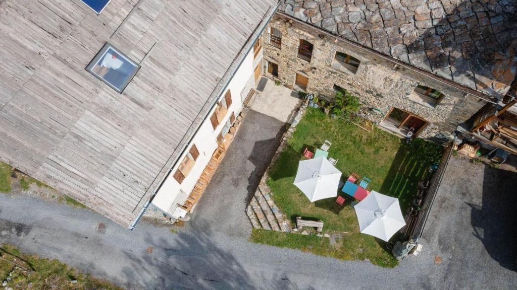 une vue sur un bâtiment avec des tables et des parasols dans l'établissement CASA-Solo Tu chambre 2 adultes 1 enfant, à Molines-en-Queyras