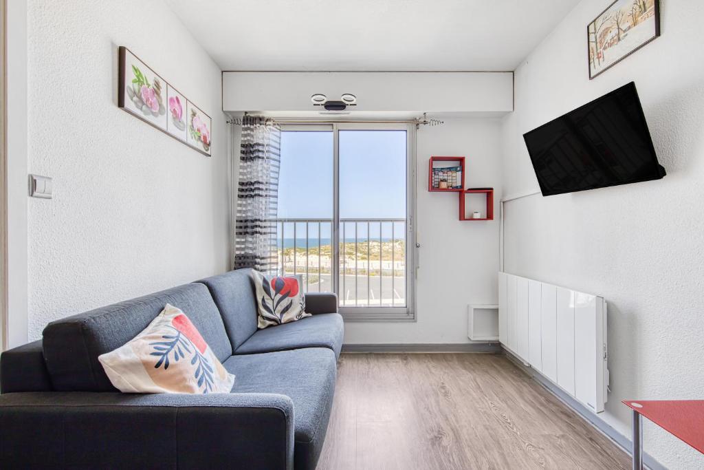 un soggiorno con un divano blu e una finestra di Appartement face à la mer a Soulac-sur-Mer