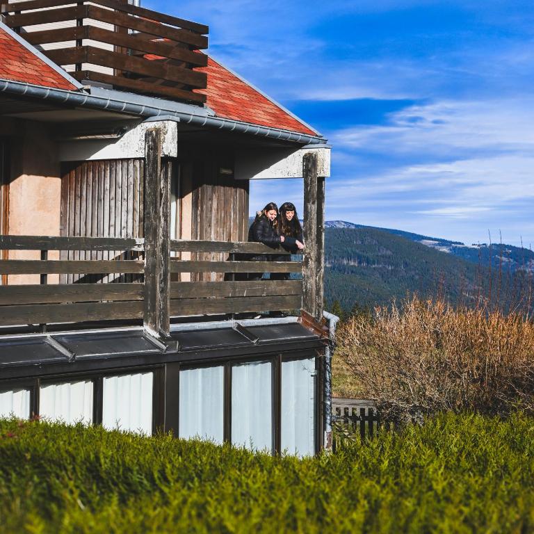 two people sitting on the balcony of a house at Le Motel du Gaschney in Muhlbach-sur-Munster