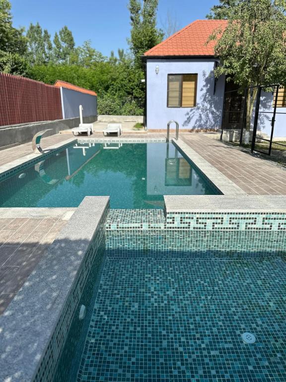 a swimming pool with a tile floor and a house at LakeSide in Gabala