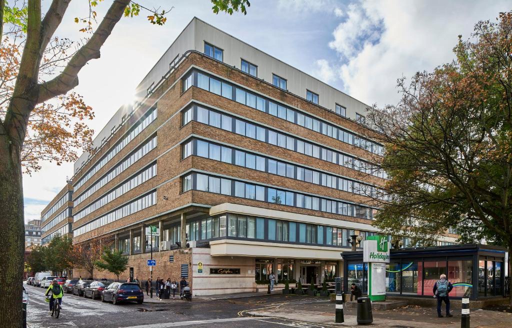 a large brick building on a city street with cars at Holiday Inn London Bloomsbury by IHG in London
