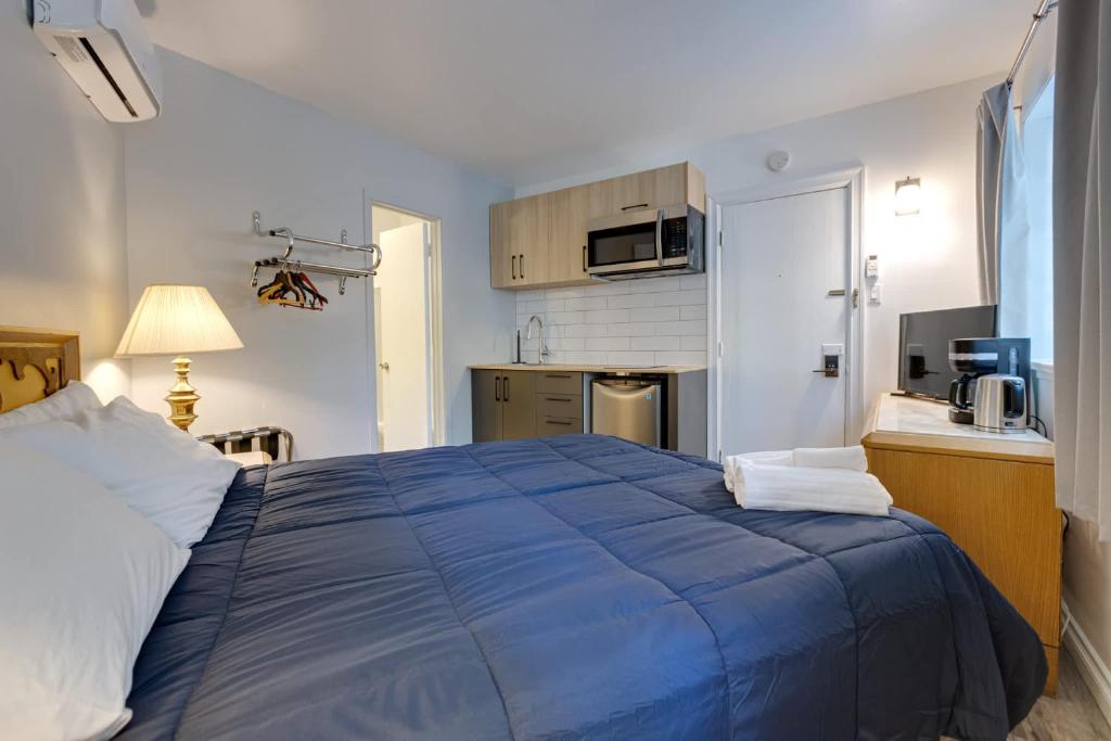 1 dormitorio con 1 cama azul y cocina en Exclusive Room - Hotel Le Cavalier by M11, en Quebec