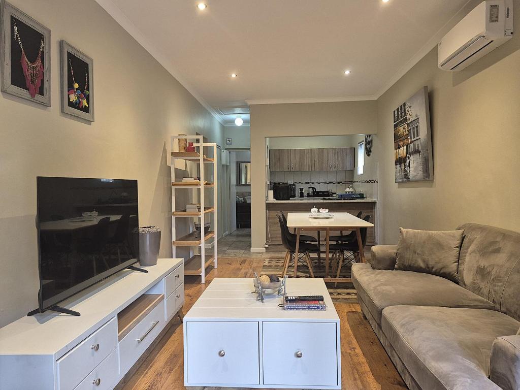Una sala de estar con un sofá y un televisor de pantalla plana. en Mistys Apartment Durbanville, en Durbanville