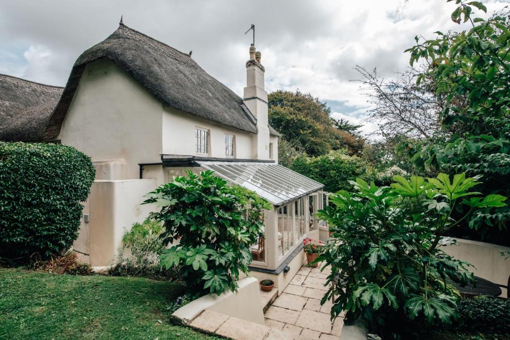 una casa blanca con un invernadero en el patio en Thatchways, en Thurlestone