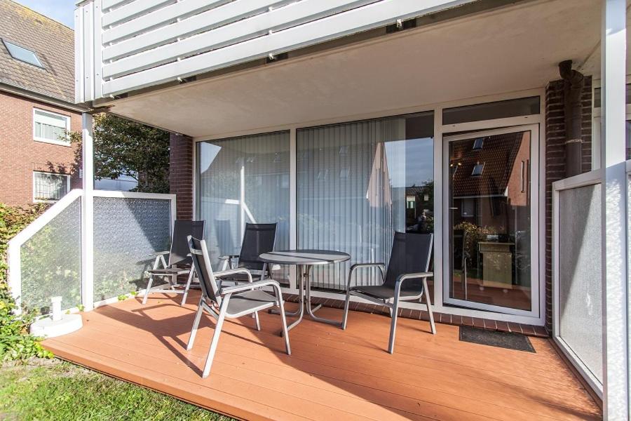 a wooden deck with a table and chairs on it at Inselschatz in Langeoog