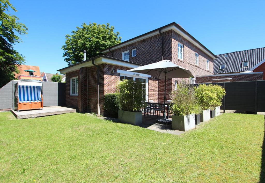 a brick house with an umbrella in the yard at Ferienhaus Stefanie 1 in Langeoog