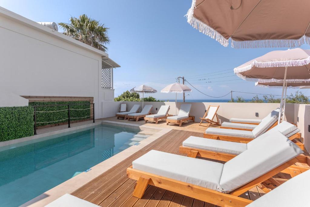 eine Villa mit einem Pool mit Stühlen und einem Sonnenschirm in der Unterkunft Bel Momento - Family Room in Alikanas