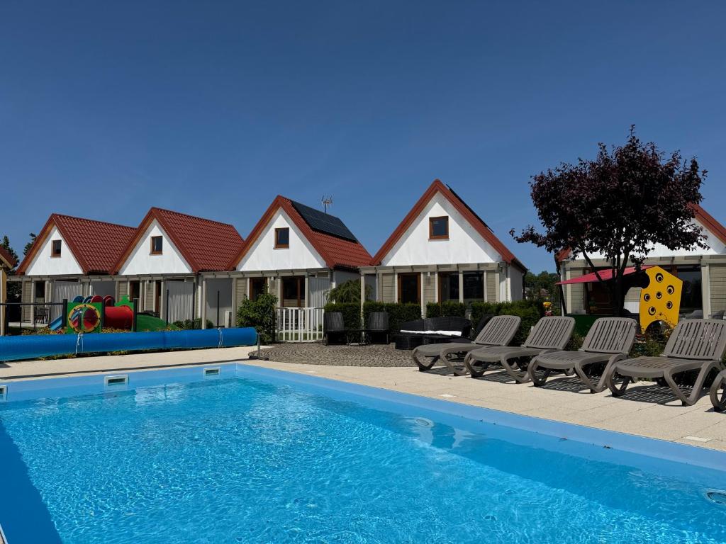 a swimming pool with two chairs and a house at KORALIA Domki Standard z basenem in Sarbinowo