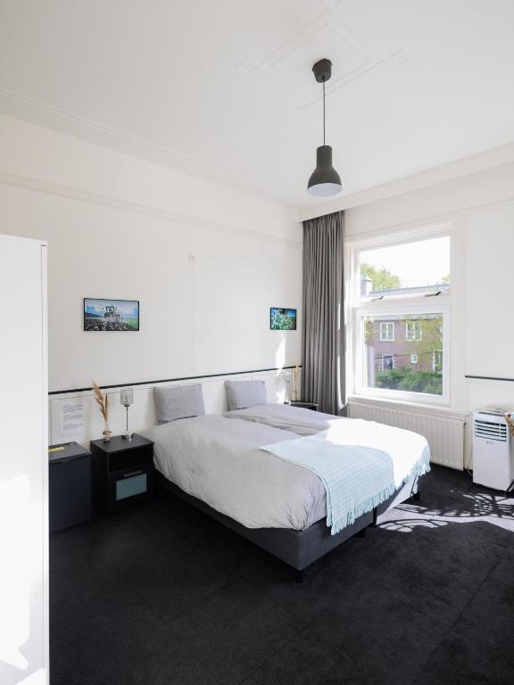 een witte slaapkamer met een groot bed en een raam bij Stad & Strandhotel Elisabeth in Vlissingen