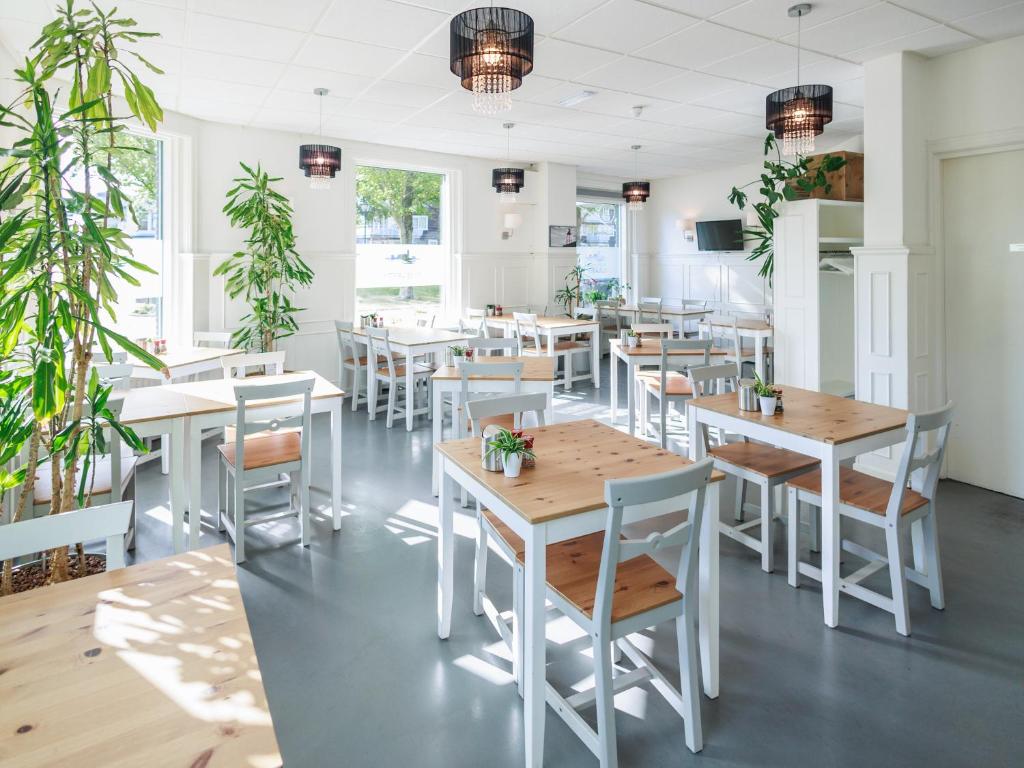 een restaurant met witte tafels, stoelen en planten bij Stad & Strandhotel Elisabeth in Vlissingen