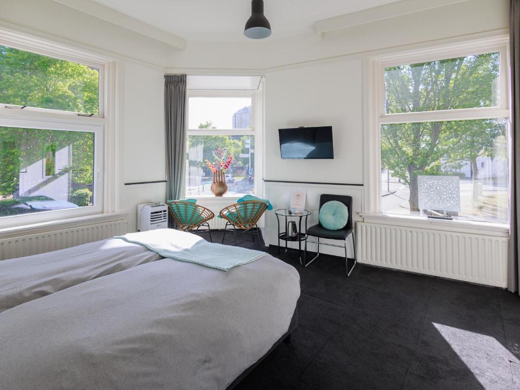 een slaapkamer met een bed en 2 stoelen en ramen bij Stad & Strandhotel Elisabeth in Vlissingen