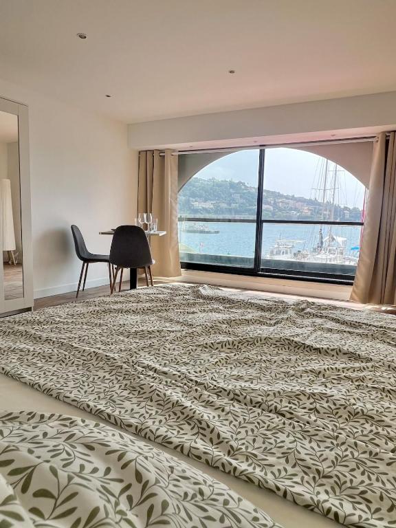 une chambre avec un grand lit et une grande fenêtre dans l'établissement 1st line sea view apartment, à Villefranche-sur-Mer