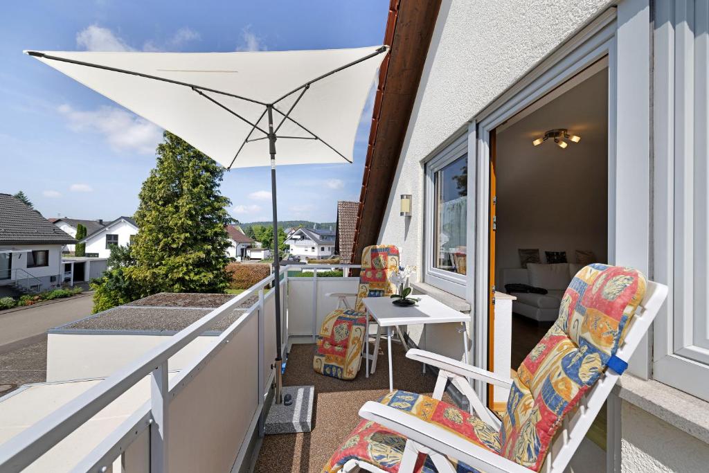 a balcony with two chairs and an umbrella at Urlaub in der Sonnenstadt 72351 in Geislingen