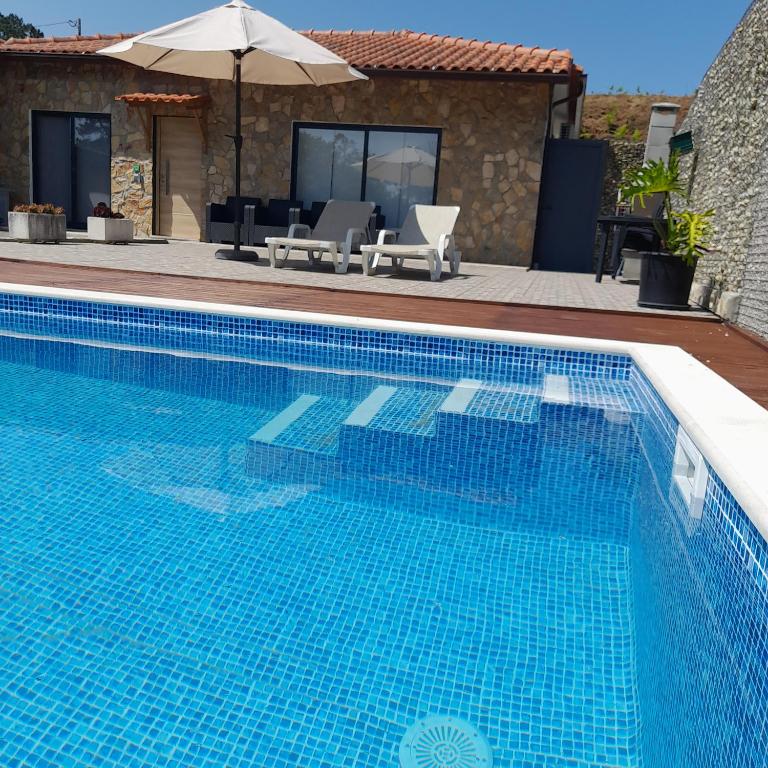 a blue swimming pool in front of a house at leiria village casa village in Leiria