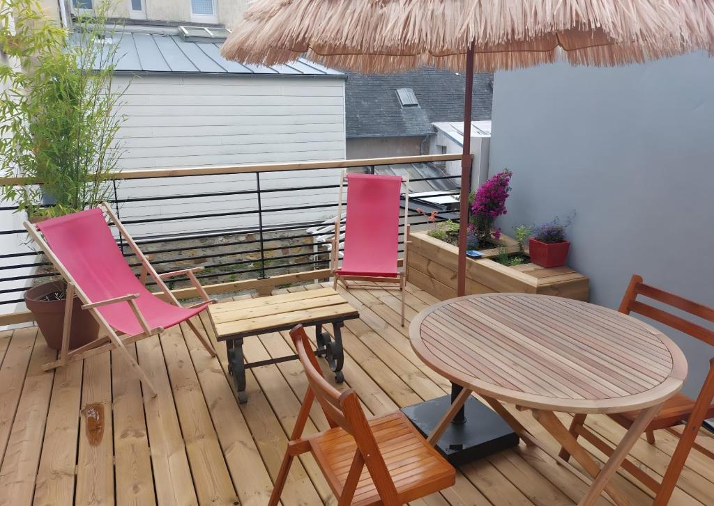 un patio avec une table, des chaises et un parasol dans l'établissement Appartement terrasse - Morgat Plage, à Crozon
