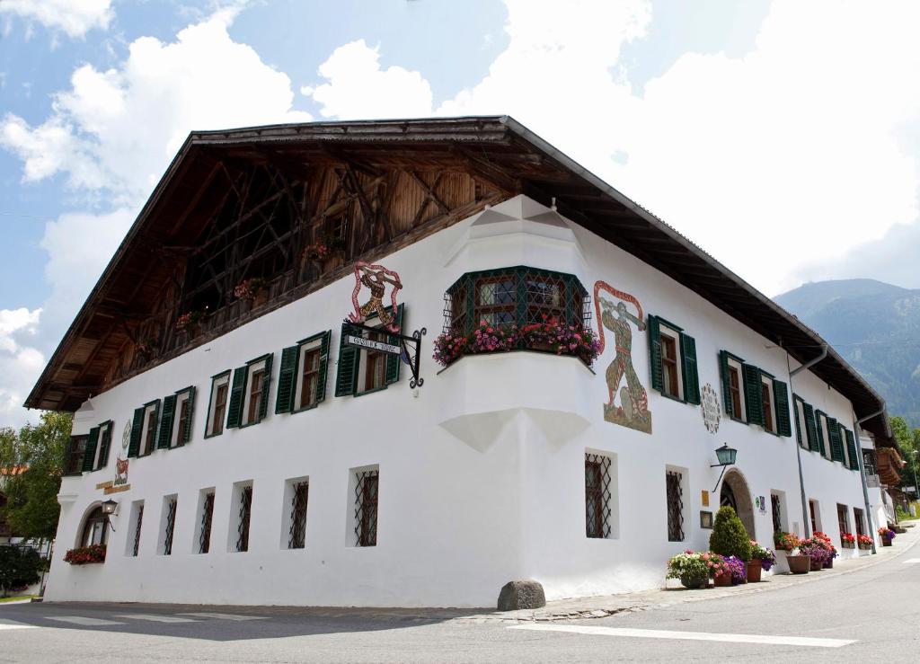 un bâtiment blanc avec un toit en gambrel dans l'établissement Landgasthof "Wilder Mann", à Innsbruck