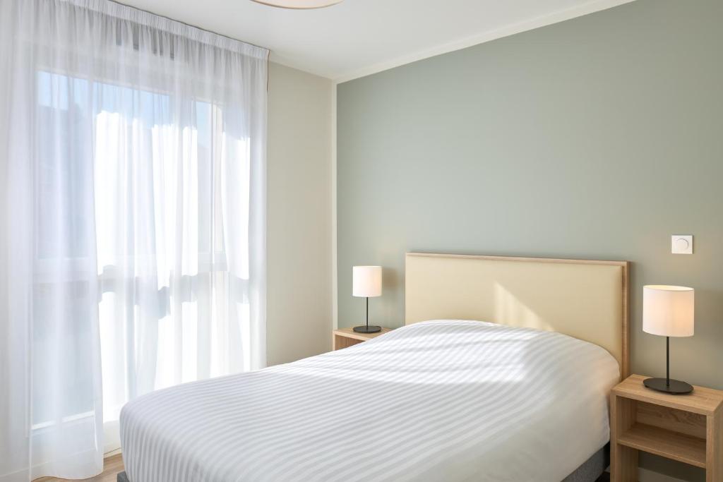 une chambre blanche avec un lit et une fenêtre dans l'établissement Zenitude Hôtel-Résidences Chambéry, à Chambéry