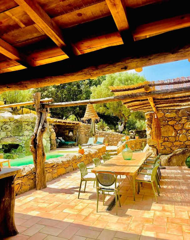 un patio avec une table et des chaises et un mur en pierre dans l'établissement La Casa D'Ange Bergerie de Luxe Piscine chauffée, à Lama