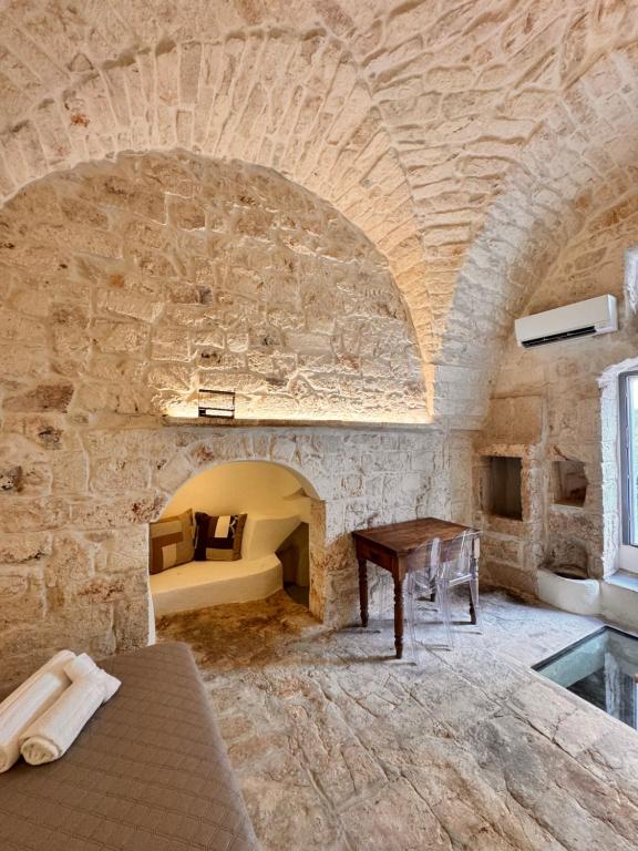 a stone walled room with a bed and a table at White Ostuni in Ostuni