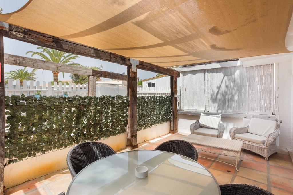 Un patio con mesa y sillas y una valla. en Oliwood Beach - Cabaret, en Playa