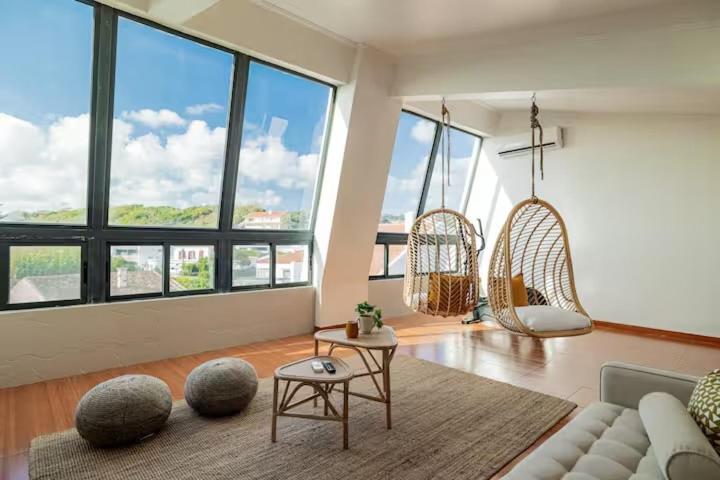 ein Wohnzimmer mit Sofa, Stühlen und Fenstern in der Unterkunft Casa de Julho - Beach House in Livramento