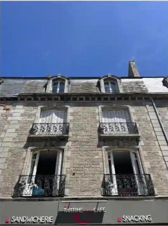 un grand bâtiment en briques avec des fenêtres et des balcons dans l'établissement Cocon sous les toits, à Dinan