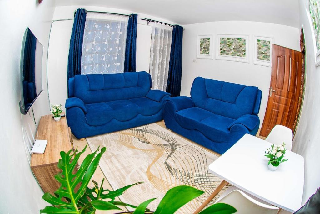 a living room with two blue chairs and a table at Hamptons Homes Stylish 1 Bedroom Stay close to Eldoret Town in Eldoret