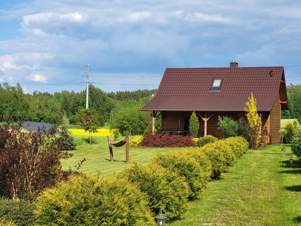 a house in a garden with a yard of bushes at Domek Jaśminowy, Domek z SAUNĄ in Brzozie