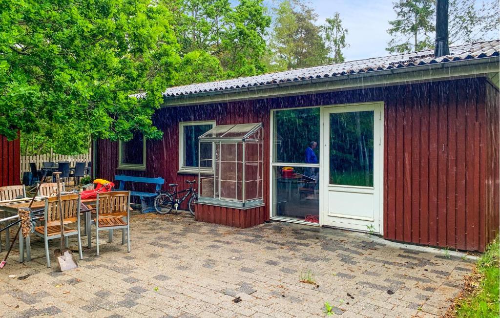 a red house with a table and chairs and a patio at Three Bedroom Cozy Home In Ebeltoft in Ebeltoft