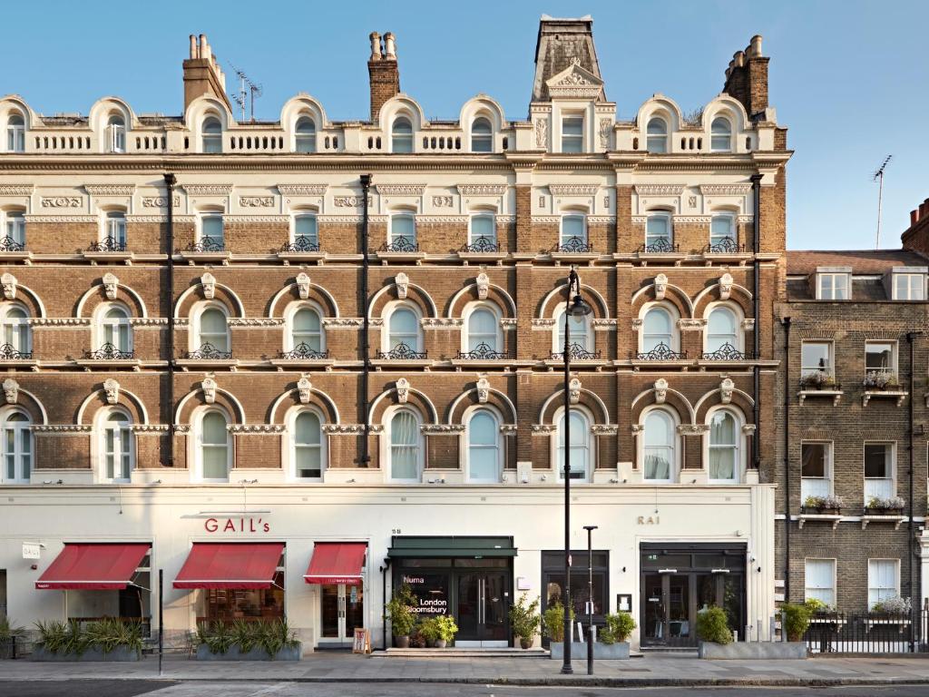 Un gran edificio de ladrillo con toldos rojos. en Numa London Bloomsbury, en Londres