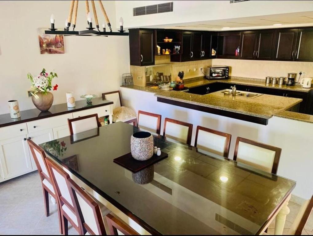 eine Küche mit einem Tisch und Stühlen sowie eine Küche mit einer Theke in der Unterkunft Town House in Veneto Residence Marassi in El-Alamein