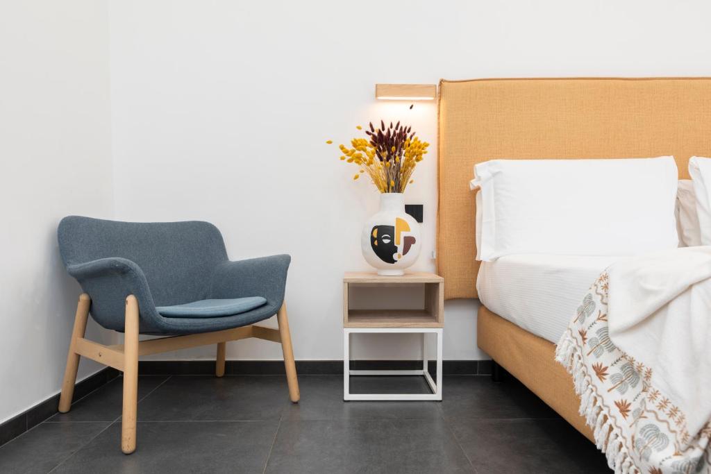 a bedroom with a bed and a chair and a vase with flowers at NG Guest House il Gallura in Olbia