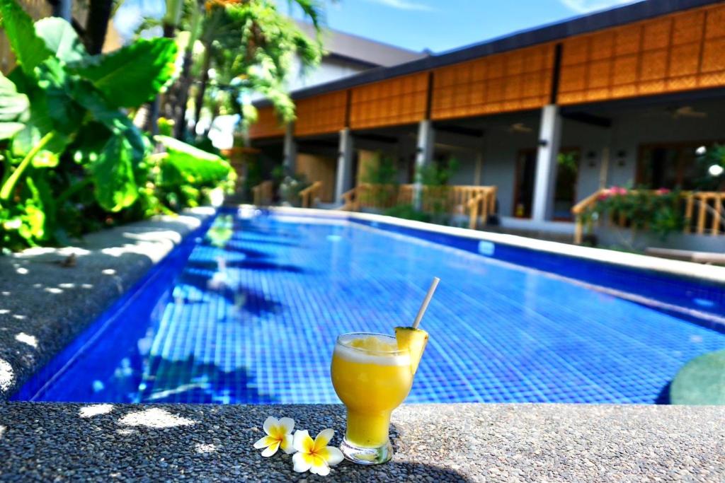 a drink sitting on a table next to a swimming pool at Mayfair Garden Resort in Panglao
