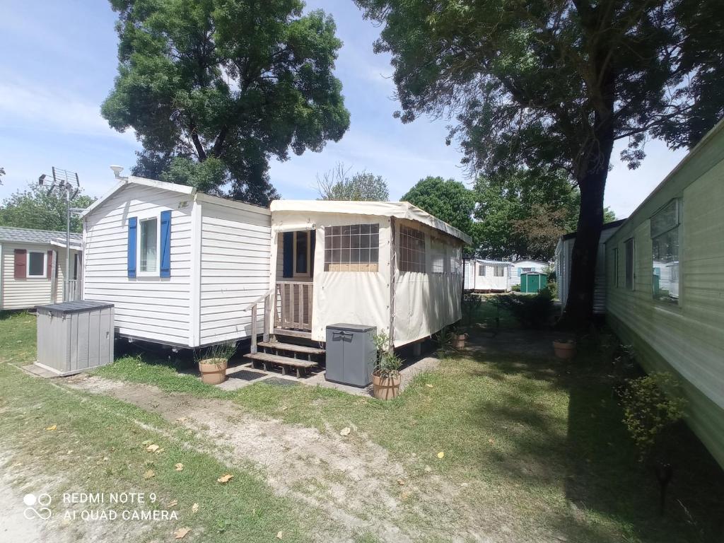 a white tiny house sitting in a yard at Mobilhome 4-6 personnes confort-piscine-mer meschers sur gironde in Meschers-sur-Gironde