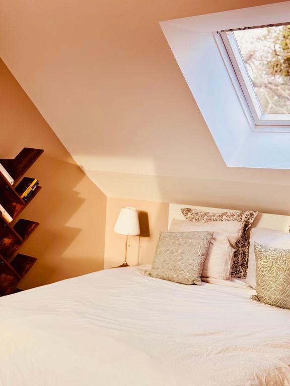 une chambre avec un lit blanc avec une lucarne dans l'établissement Au petit Cachou, à Port-Bail-sur-Mer