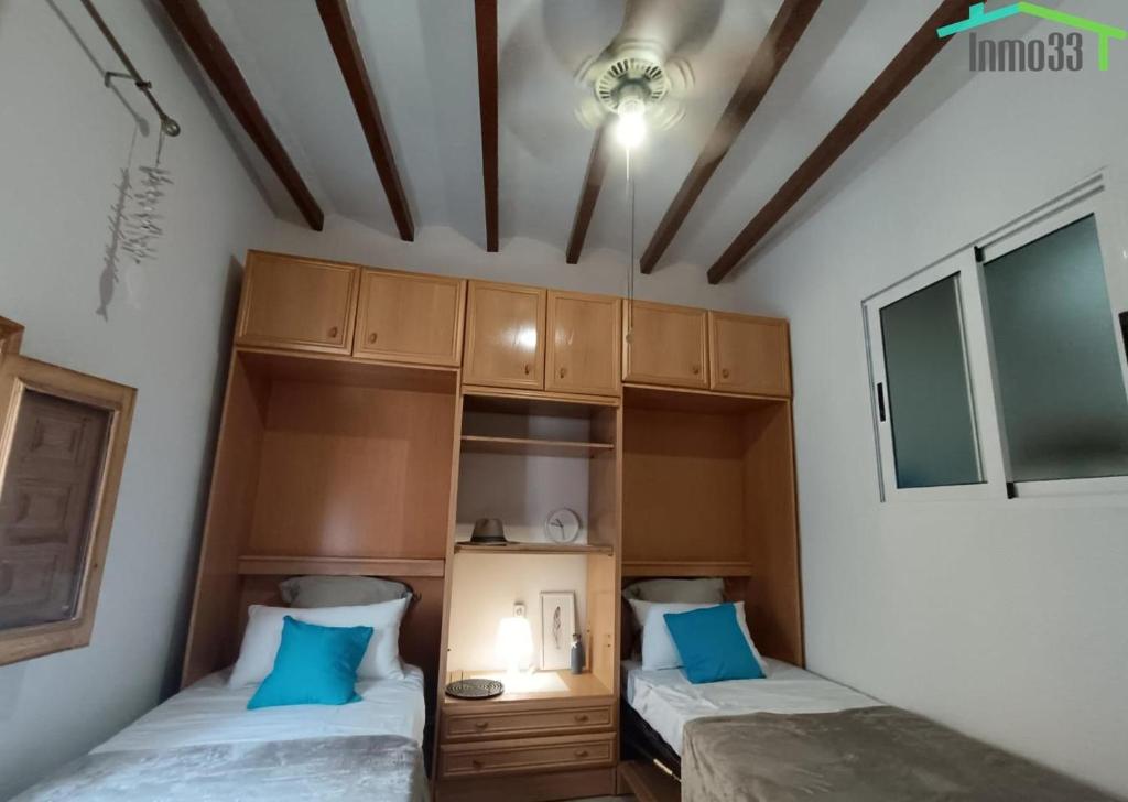 two beds in a room with blue pillows at Casita de Pescadores en La Costera in Villajoyosa