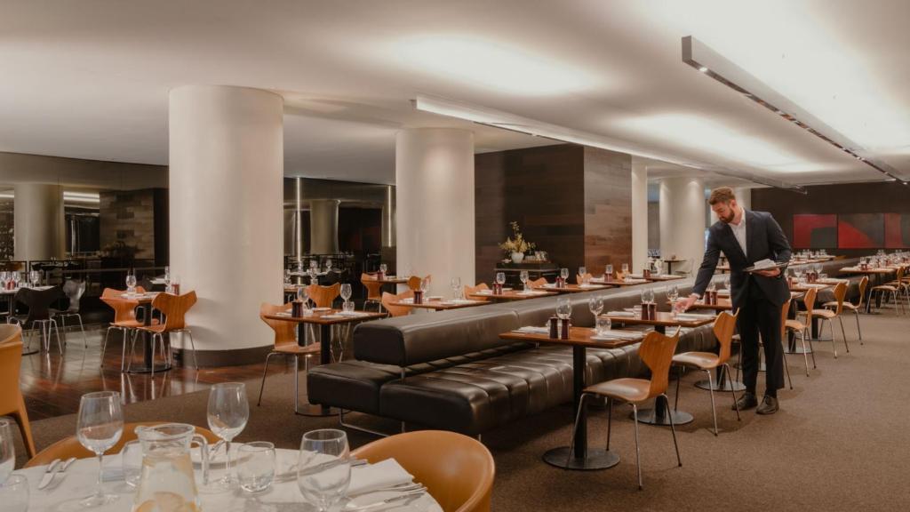 a man standing in a restaurant with tables and chairs at InterContinental Brisbane by IHG in Brisbane