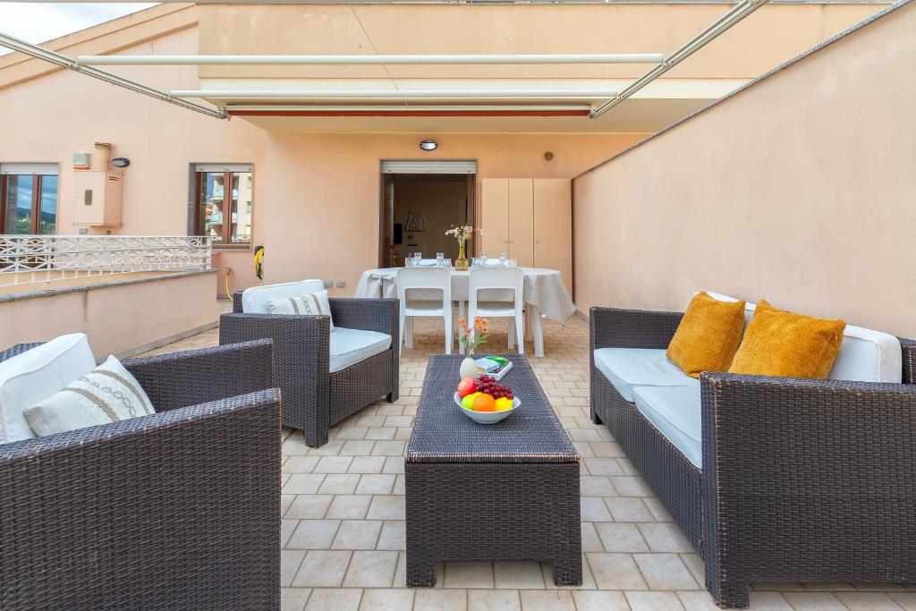 a patio with wicker furniture and a table with a bowl of fruit at SARDINIA RE - Libero 22 - Free Parking in Alghero