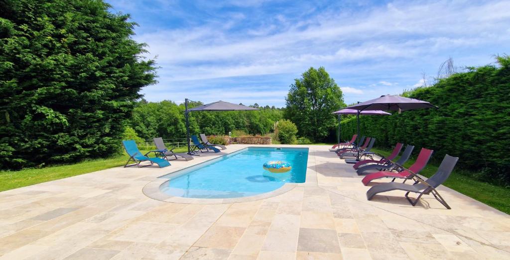 een zwembad met stoelen en parasols op een patio bij Les Granges Indigo in Fossemagne