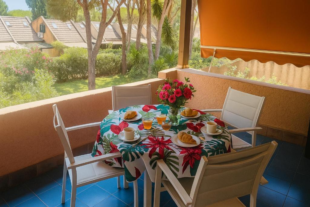 a table with flowers and plates of food on a balcony at Casa a Calaverde pochi passi dal mare terrazza aria condizionata WiFi e parcheggio in Forte Village