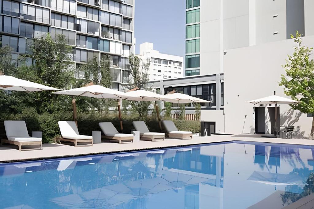 a pool with chairs and umbrellas next to a building at Sao Paulo Vertical in Guadalajara