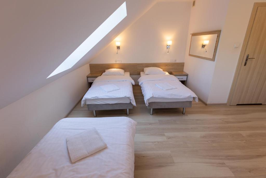 Attic bedroom with two single beds, skylight, and wooden flooring.