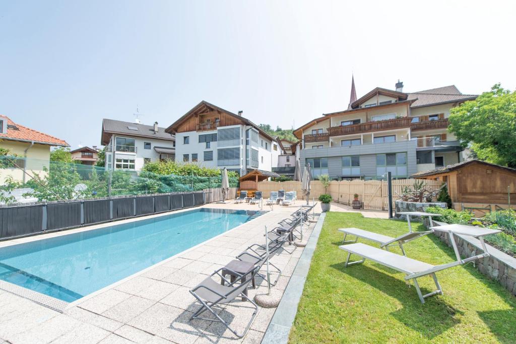 a swimming pool with lounge chairs next to some buildings at Gasthof Teiser Stern in Funes