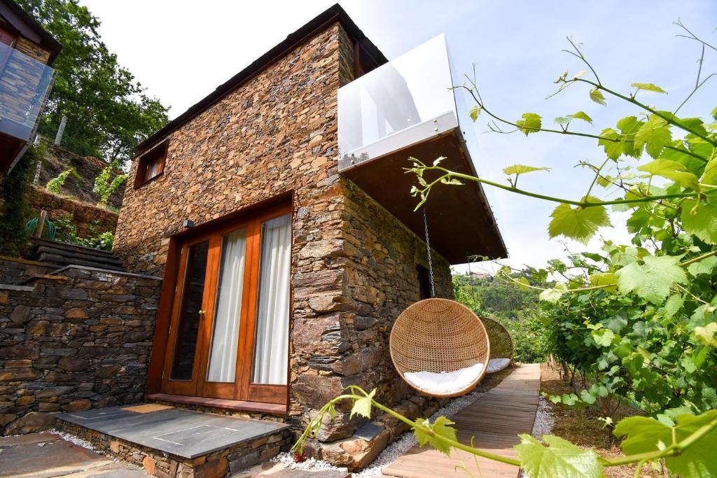 a brick house with a rattan chair on a porch at Moinhos do Paiva in Castelo de Paiva