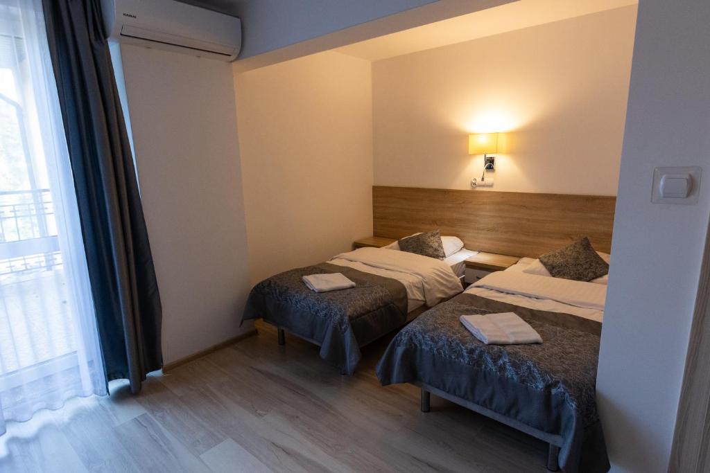 Dimly lit room with two single beds and a large window.