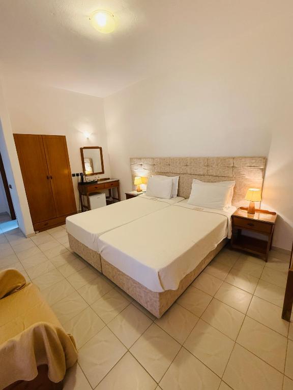 a bedroom with a large white bed and two tables at Asteri Hotel in Livadi